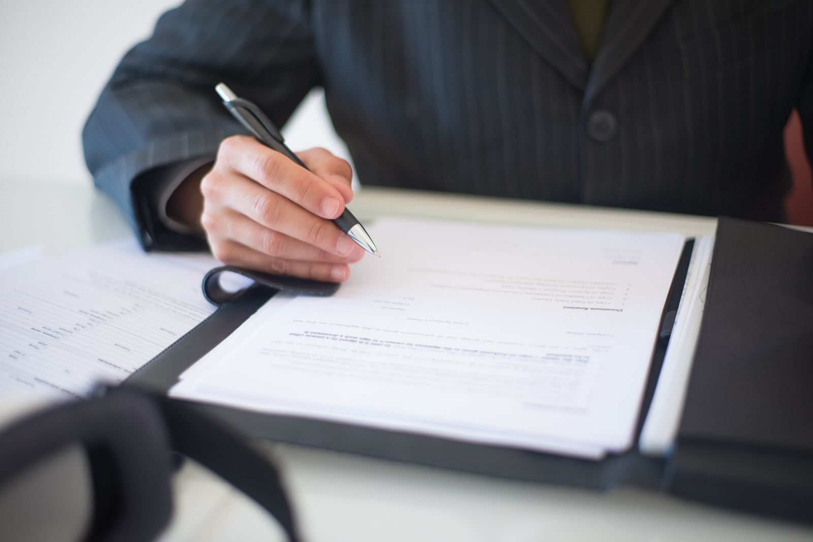 Close-up of a hand signing property documents with a pen